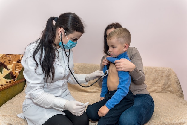 Pediatrician checking heartbeat of little patient on visit