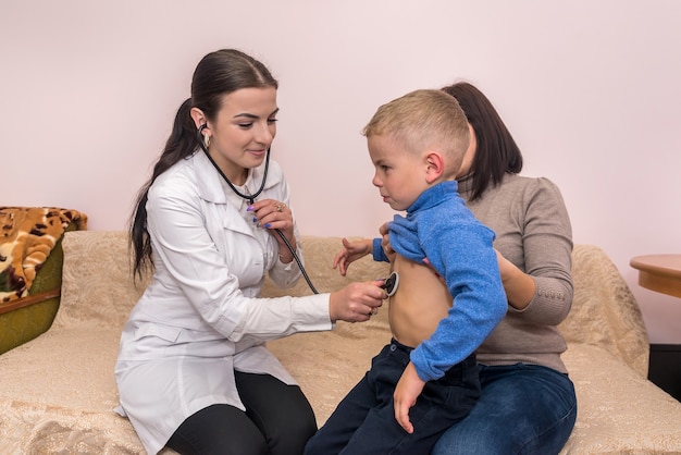 Pediatrician checking heartbeat of little patient on visit