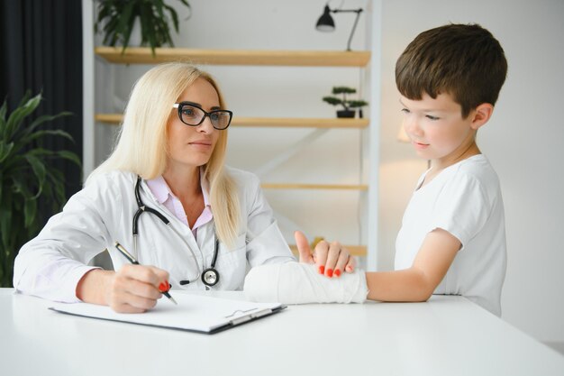 Pediatrician doctor bandaging child's arm Broken arm in a boy