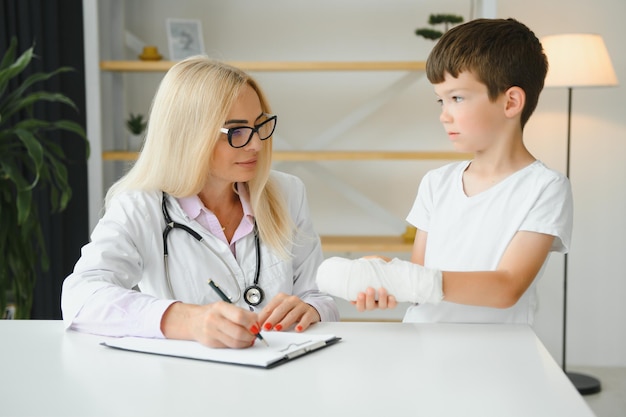 Pediatrician doctor bandaging child's arm Broken arm in a boy