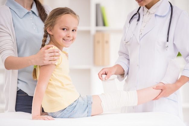 Pediatrician doctor bandaging child's leg.