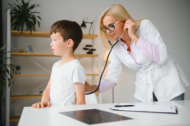 Pediatrician doctor examining little boy's heart beat and lungs to check for problems