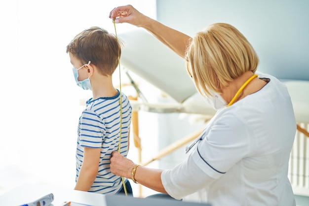 Pediatrician doctor examining little kids in clinic measure tape. High quality photo