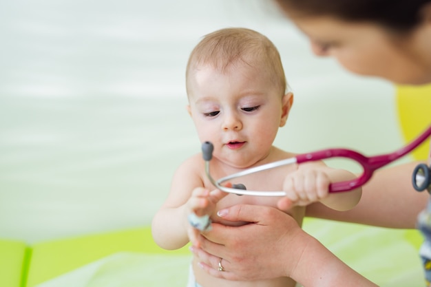 소아과 의사는 청진 클리닉에서 작은 아기를 검사합니다. 좋은 귀여운 작은 환자. 어린이 건강 개념,