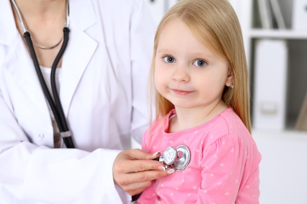 Pediatrician is taking care of baby in hospital little girl is being examine by doctor by stethoscope health care insurance and help concept