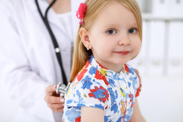 Педиатр заботится о ребенке в больнице Маленькую девочку осматривает врач с помощью стетоскопа Медицинское страхование и концепция помощи