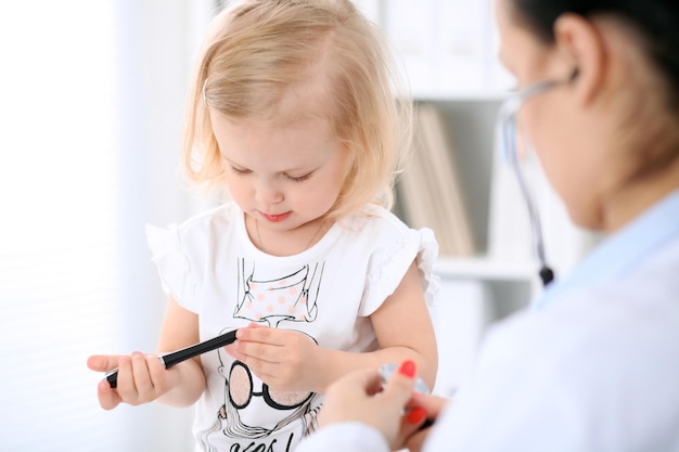 Педиатр заботится о ребенке в больнице Маленькую девочку осматривает врач со стетоскопом Медицинское страхование и концепция помощи