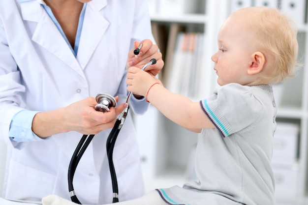 Pediatrician is taking care of baby in hospital Little girl is being examine by doctor with stethoscope Health care insurance and help concept