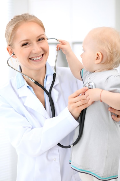 Pediatrician is taking care of baby in hospital. Little girl is being examine by doctor with stethoscope. Health care, insurance and help concept.