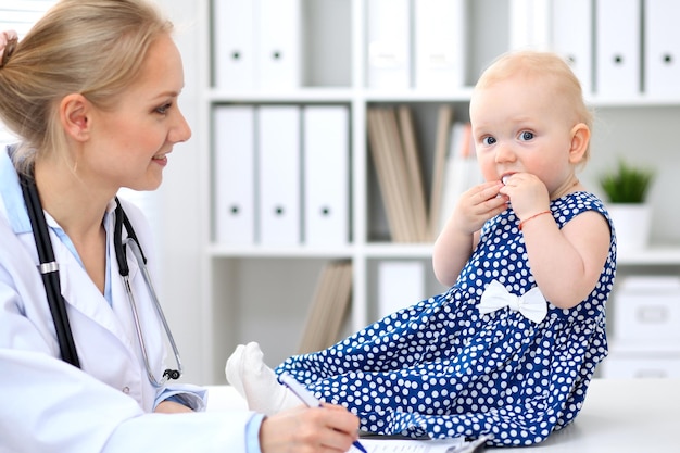 Pediatrician is taking care of baby in hospital. Little girl is being examine by doctor with stethoscope. Health care, insurance and help concept.