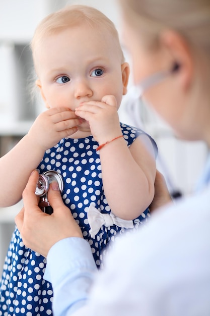 소아과 의사가 병원에서 아기를 돌보고 있다 어린 소녀가 의사에게 청진기로 검사를 받고 있다