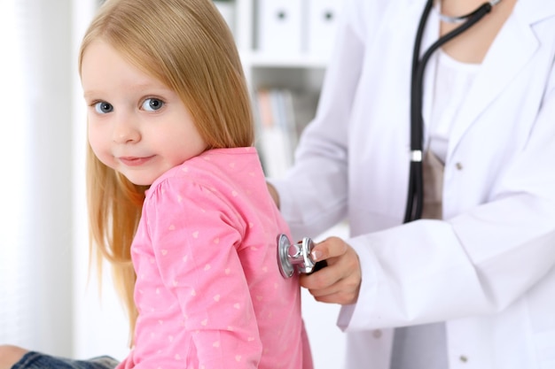 Фото Педиатр заботится о ребенке в больнице маленькую девочку осматривает врач с помощью стетоскопа медицинское страхование и концепция помощи