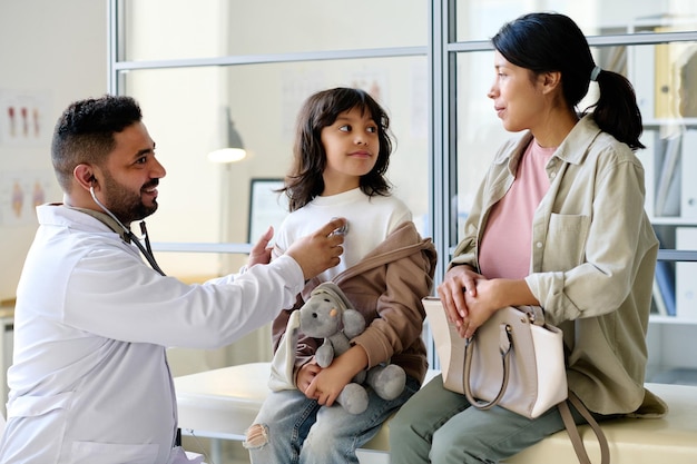 Photo pediatrician listening to heartbeat of child with stethoscope during medical exam in hospital