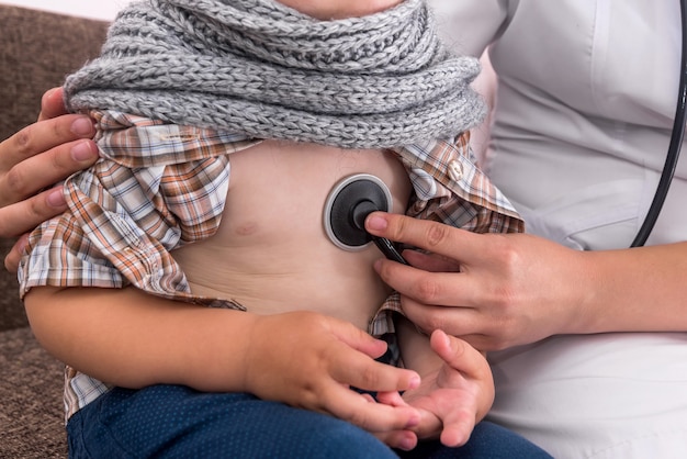 Pediatrician listening to kid's heartbeat in hospital