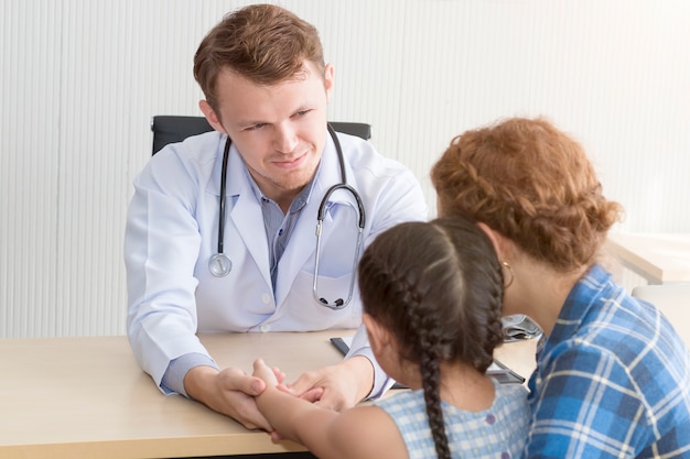 Pediatrician man examining, reassuring and discussing child at surgery 