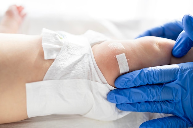 Photo pediatrician sticking patch on baby leg after vaccine injection