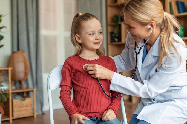 Pediatrician visiting her little patient at home woman in uniform listening to child patient breath with stethoscope