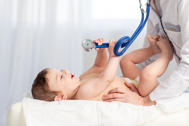 소아과 의사가 아기를 검사하고 청진기를 사용하여 아이의 호흡, 의학 및 건강의 개념을 듣습니다.
