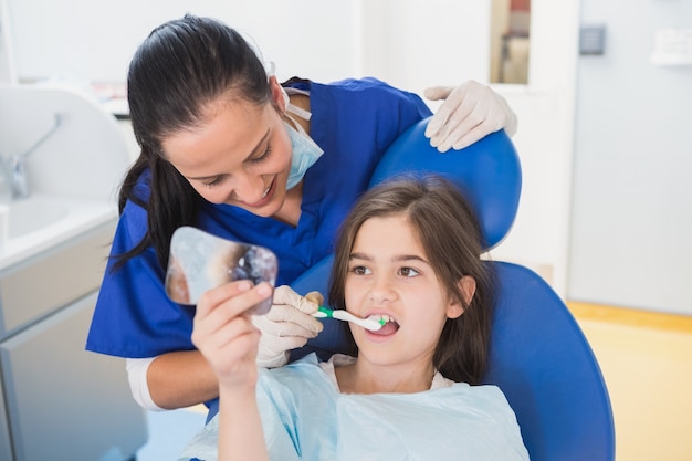 Pediatrische tandarts die tanden borstelt aan haar jonge patiënt