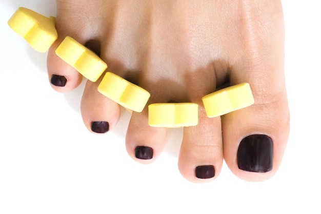 Photo pedicure. beautiful female feet with shellac coating on the nails, on a white isolated background. finger separator