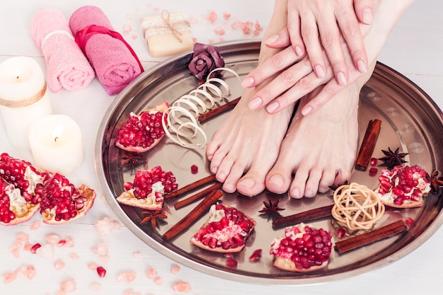 Pedicure and manicure in the spa salon with pomegranate, cinnamon and anise on a white wooden table