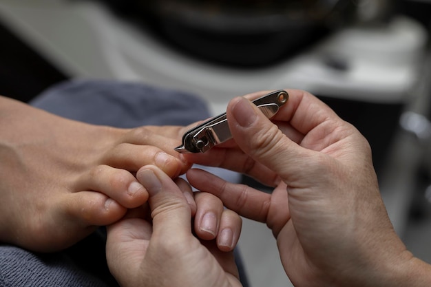 A pedicure salon employee uses a pair of pliers to cut toenails