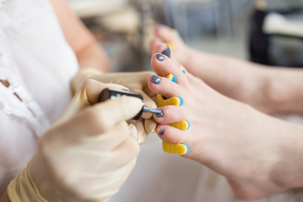 Pedicurist applying nail polish