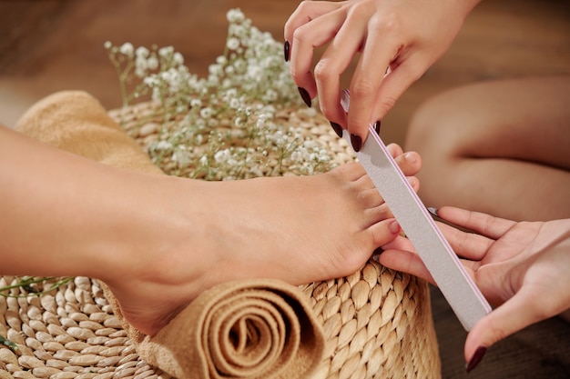 Pedicurist filing toenail