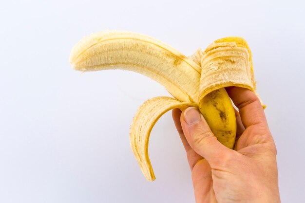 A peeled banana in a woman's hand on white