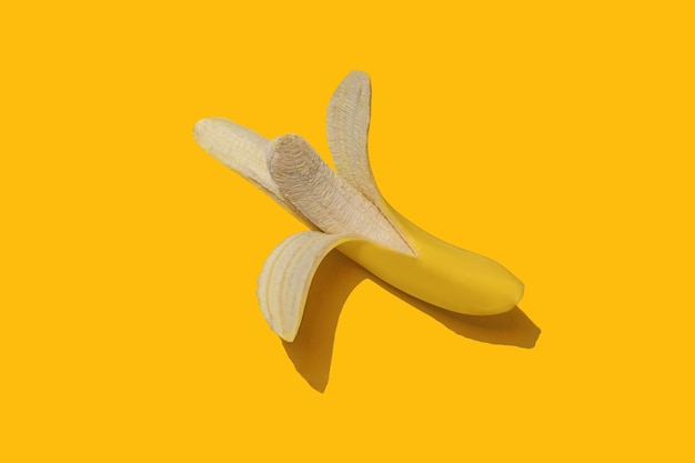 Peeled banana on yellow background