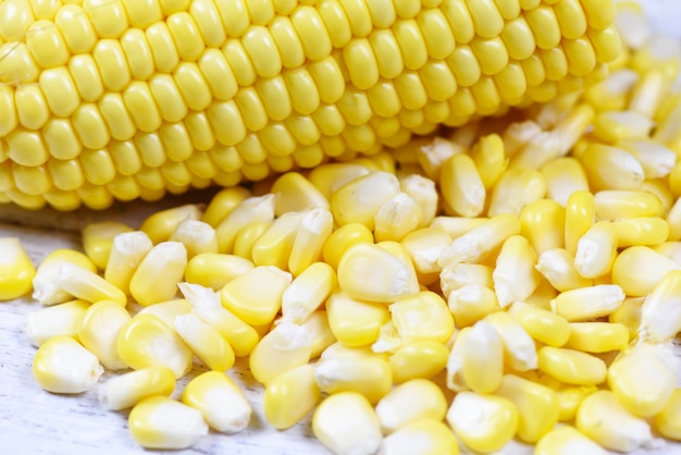 Peeled ear of corn on the cob - Fresh corn seeds on white wooden background