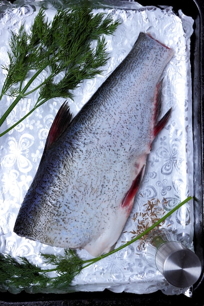 皮をむいた魚の死骸がデコの上に横たわっています。スパイスと銀箔の鯉。グリルで焼く準備ができました