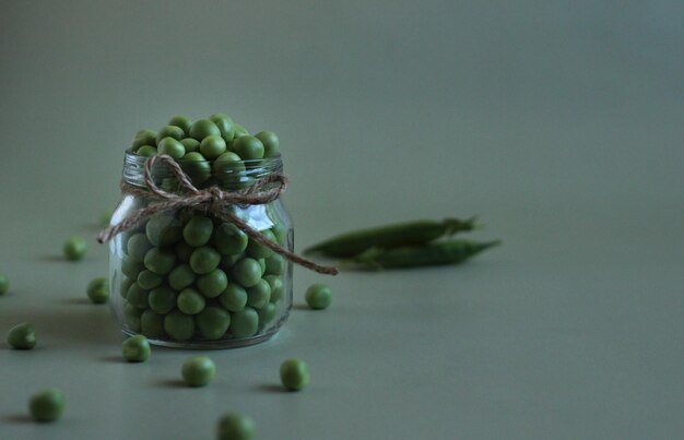 Peeled green peas in a glass jar on a gray background