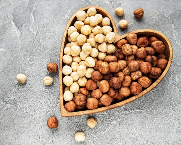 Peeled hazelnuts in a bowl on grey concrete background