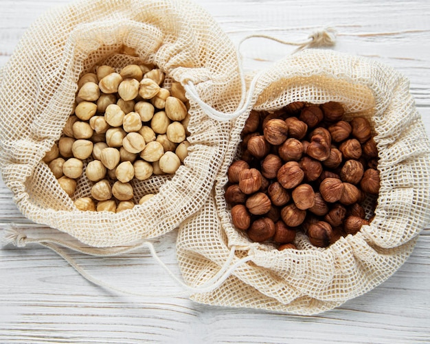 Peeled hazelnuts in a cotton bags on white wooden background