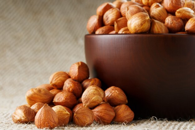 Photo peeled hazelnuts in a wooden, dark brown cup on a burlap cloth