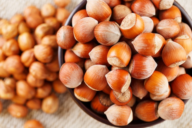 Peeled hazelnuts in a wooden, dark brown cup on a burlap cloth