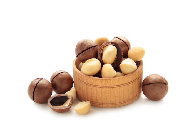 Photo peeled macadamia nuts in wooden bowl isolated on white background.