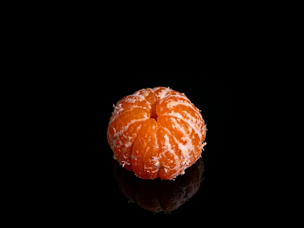 Peeled mandarin fruit slices on a black background