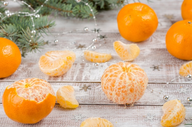 Peeled mandarin on a wooden background with branches of spruce. New year and christmas background.