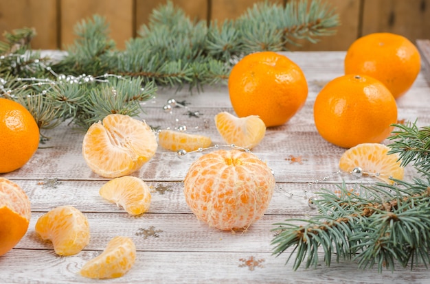 Peeled mandarin on a wooden background with branches of spruce. New year and christmas background.