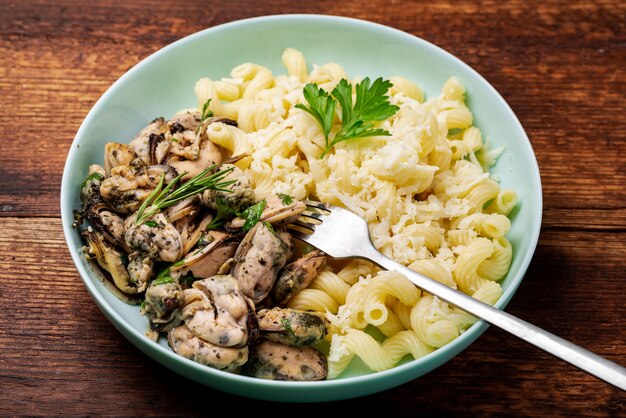 Peeled mussels with pasta on a dark wooden background