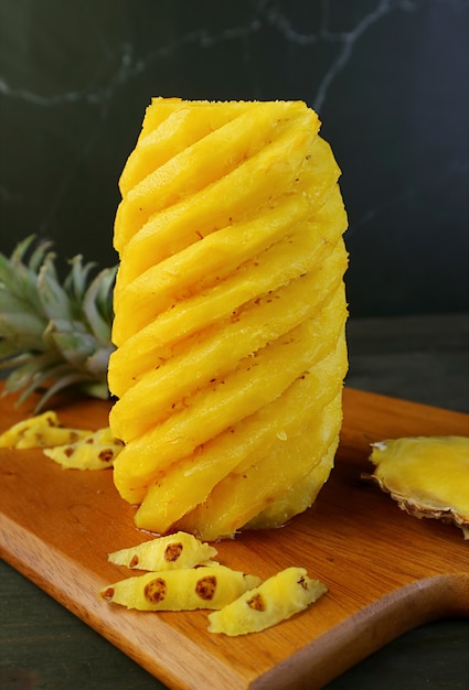 Peeled and nicely cut fresh ripe pineapple on a wooden cutting board