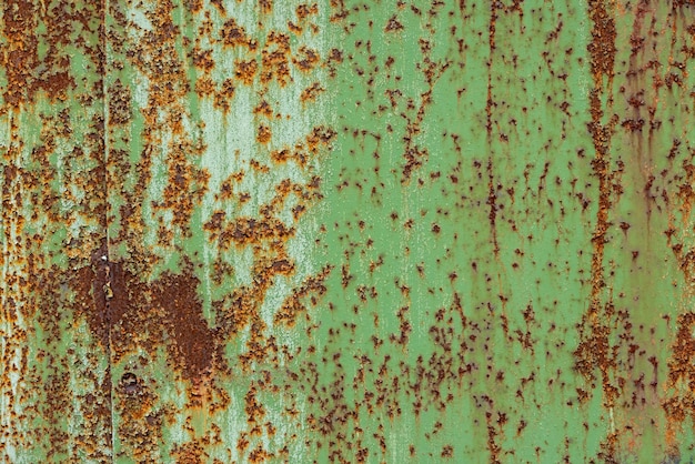 Peeled off green paint on flat rusted sheet metal surface