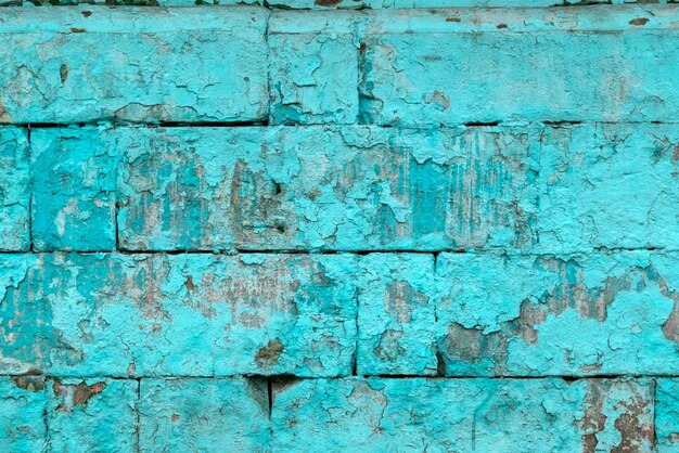 Peeled off old turquoise paint on flat rough brick wall surface
full frame background and texture