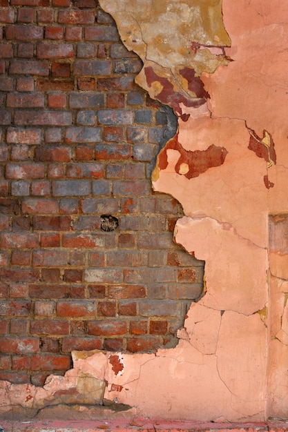 Peeled off pink plaster on old red brick wall flat full frame\
background and texture