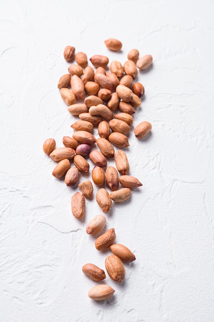 Peeled peanuts on white concrete textured background