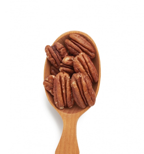 Peeled pecans in a brown wooden spoon isolated on white space