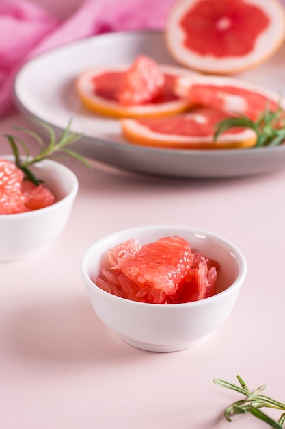 Peeled pieces of grapefruit and rosemary in a bowl on the table Cocktail ingredients Vertical view