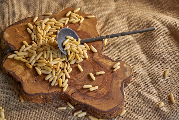 Peeled pine kernels, pine nuts on a slice of wood with an antique spoon.